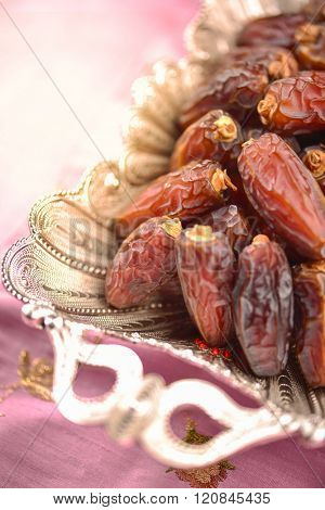 Heap of dates in a silverware. An extreme closeup with selective focus treatment.