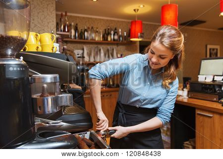 equipment, coffee shop, people and technology concept - barista woman making coffee by machine at cafe bar or restaurant kitchen