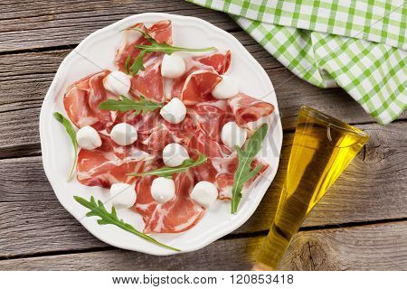 Prosciutto and mozzarella on wooden table. Top view