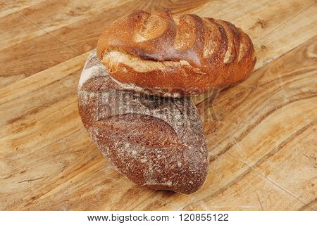 different rye and white flour french bread loaf with on light wooden table background
