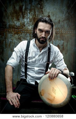Handsome man posing in white shirt holding hand drum