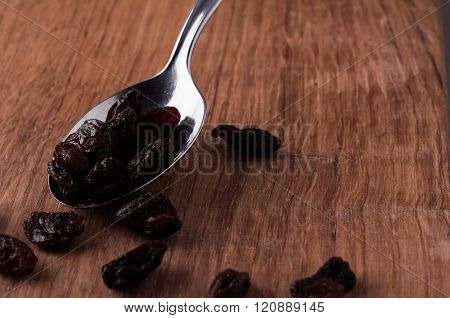 Risins On Metal Spoon On Brown Wooden Table