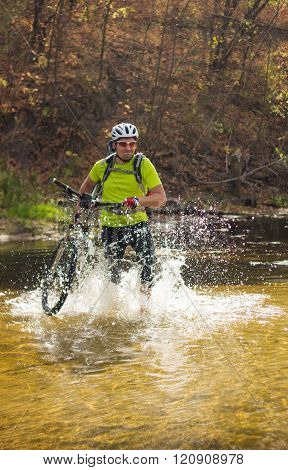 A man passes a river with a bicycle on his shoulder in a helmet and a backpack.