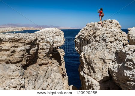 Young lady taking picture from top of the cliff in the National Park of Ras Muhammad, Egypt