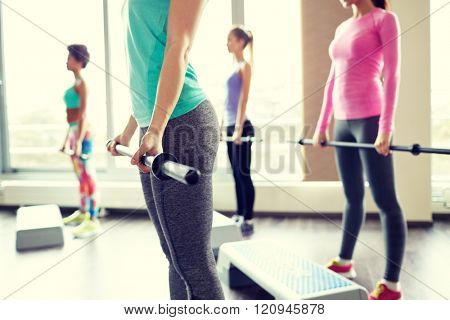 fitness, sport, people and lifestyle concept - close up of women exercising with bars and step platforms in gym