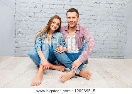 Happy Pretty Man And Woman Sitting Barefoot On The Floor
