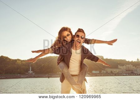 Happy Man Carring His Gilfriend On The Back At The Seaside