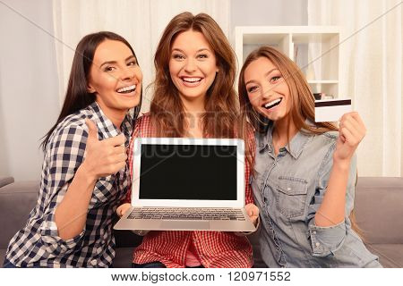Cheerful Girls Showing Laptop, Bank Card And Gesturing