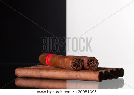 Different cigars on a glass table and black and white background