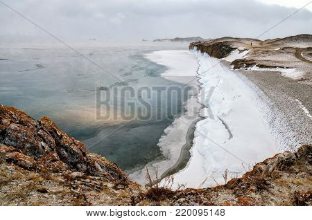 Baikal Lake and rock in the December cold. Time of freeze-up. Ice floes is swiming on the water. Siberia, Russia