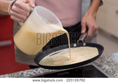 Pancake dough is poured into hot frying pan - close-up pancakes