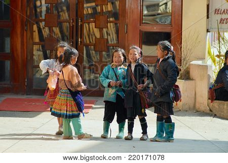 SAPA, VIETNAM - FEBRUARY 10, 2007: Unidentified kids of the Black Miao (Hmong) minority hill tribe wearing traditional costumes talk at the street in Sapa, Vietnam.