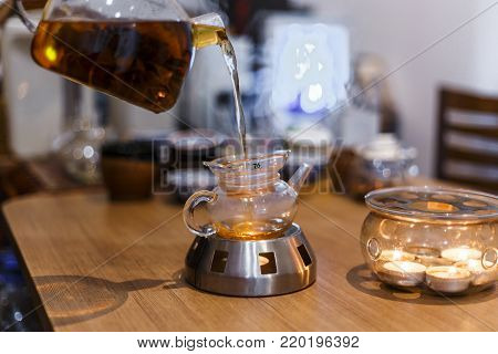 Blooming flower Tea is poured from a teapot into a cup.