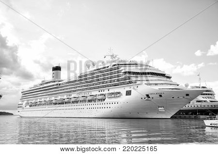 St. John, Antigua - March 05, 2016: beautiful large cruise ship, big white passenger boat, luxury modern Costa Magica vehicle at moorage in sea port, pier with people summer day on blue cloudy sky