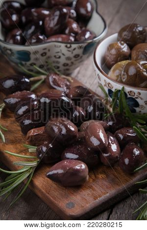 Cured, pickled or brined olive fruit on wooden table