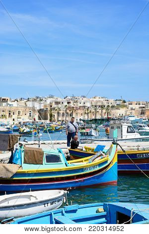 MARSAXLOKK, MALTA - APRIL 1, 2017 - Traditional Maltese Dghajsa fishing boats in the harbour with waterfront buildings to the rear, Marsaxlokk, Malta, Europe, April 1, 2017.