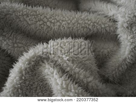Soft and fuzzy folds are created within this crumpled warm beige blanket