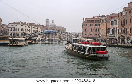 Venice, Italy - October 13, 2017: The Canale Grande in the district of the railway station. Pleasure boats, river trams, and boats are floating along the canal. Tourists are walking along the bridge.