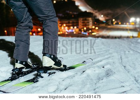 ski legs close up with snowed mount in evening on background