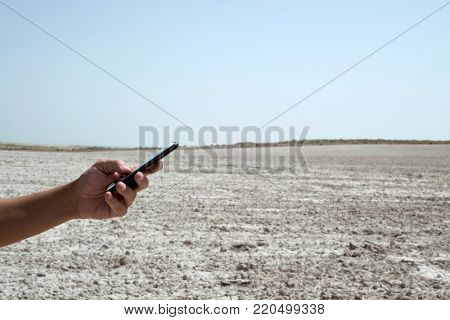 closeup of a young caucasian man man using a smartphone in the desert