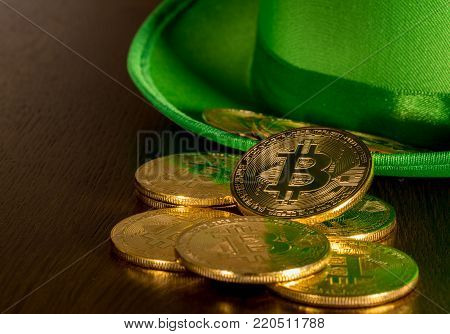 Treasure of golden bitcoins inside a green velvet hat on wooden table to celebrate luck on St Patrick's Day of March 17th