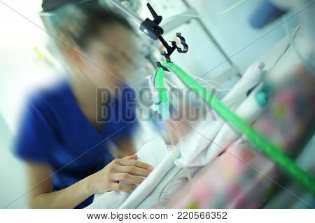 Female doctor working with the baby patient in the newborn intensive care unit.