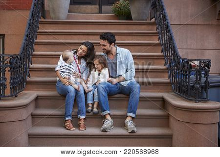 Young family with kids sitting on front stoops