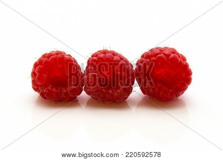Three red raspberries in row isolated on white background