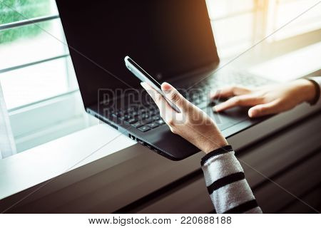 Woman holding mobile phone and using laptop computer with shopping onling,Selective focus