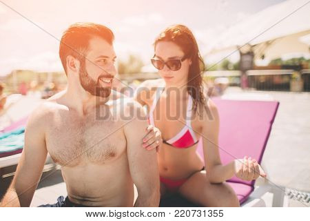Couple applying suncream. Happy young woman applying cream on boyfriend's back