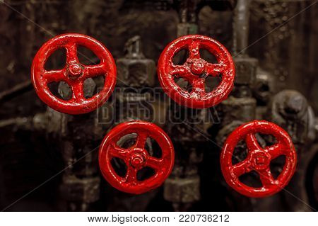 Four red valves on the bruwn wall in old engine