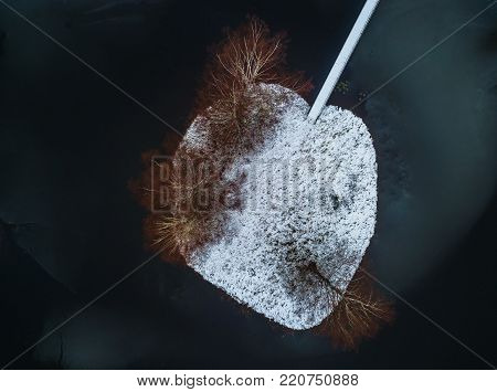 Nice aerial drone photography of a heart shaped snowy island with trees in winter