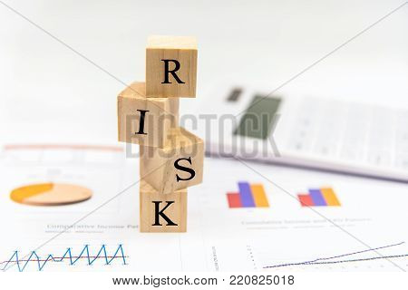 Risk in business investment. Word risk white in the wood block on paper analyse financial graph.  Investment Concept.