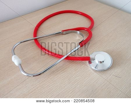 red medical stethoscope laid in a wooden bench