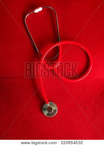 red medical stethoscope in a red velvet background