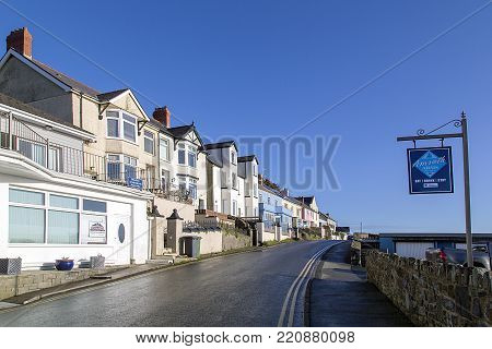 Amroth, UK: January 01, 2018: The main street through the quaint seaside village of Amroth with pastel painted bed and breakfast hotels. Double yellow lines prevent parking on the narrow road.