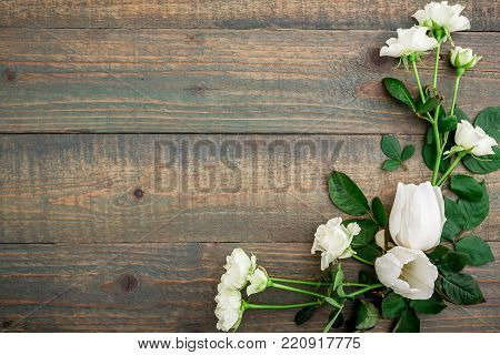 Floral background. Floral frame made of white flowers and green leaves isolated on wood background. Flat lay, top view.