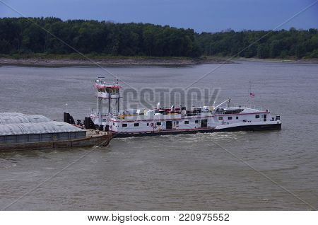Tug pushing barges on Mississippi River with treelines shore