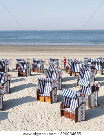 Norderney, Germany, 25 August 2019: Man In Red Shirt Checks Beach Korbs On The Island Of Norderney I