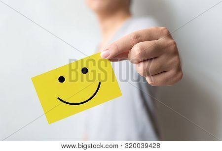 Customer Service Experience And Business Satisfaction Survey. Man Holding Yellow Card With Smiley Fa
