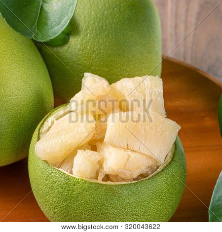 Fresh Peeled Pomelo, Grapefruit, Shaddock With Green Leaves On Dark Wooden Plank Table. Seasonal Fru
