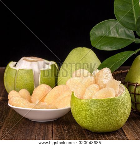 Fresh Peeled Pomelo, Grapefruit, Shaddock With Green Leaves On Dark Wooden Plank Table. Seasonal Fru