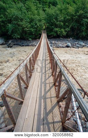 Hanged Rope Bridge Over The Fast Muddy River