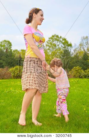 Matka s dcerou chůze naboso na trávníku