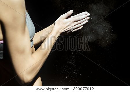 Woman Climber Is Clapping Hands With White Chalk Powder Before Climb In Indoor Climbing Gym On Black