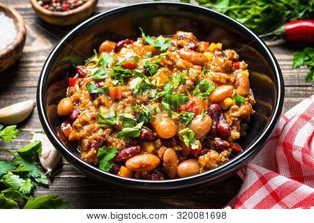 Chili Con Carne With Meat, Beans And Vegetables On Dark Wooden Table Close Up. Traditional Mexican F