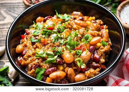 Chili Con Carne With Meat, Beans And Vegetables On Dark Wooden Table Close Up. Traditional Mexican F