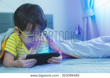 Cute Little Child Watch Movie On Smartphone At Bed. Dangers Of Blue Light Can Damage Eyes. Handsome 