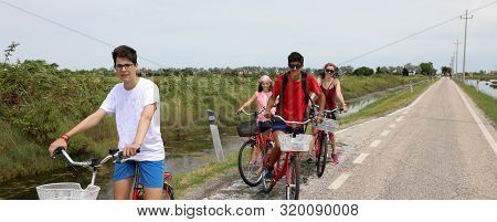 Borthers And Sister With Mother On The Bikes In Summer