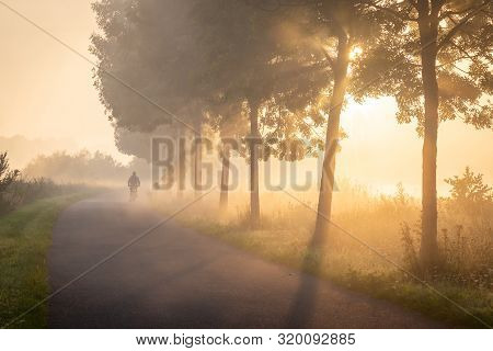 Cyclist In The Fog On The Towpath Along The Lys In Lauwe - Menen, Belgium. After A Cold And Clear Ni
